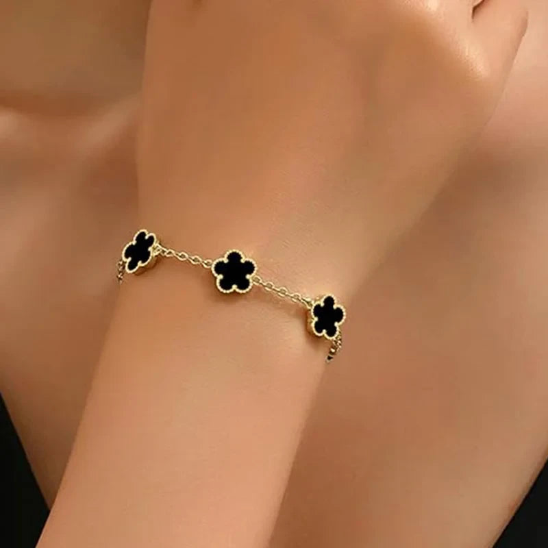 Double Sided Clover Charm Bracelet worn on wrist showcasing black clover charms and gold accents.