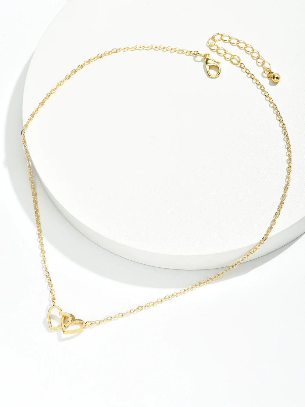 Double Hollow Heart Chain Necklace displayed on a white surface, featuring a charming gold design with two hollow hearts.